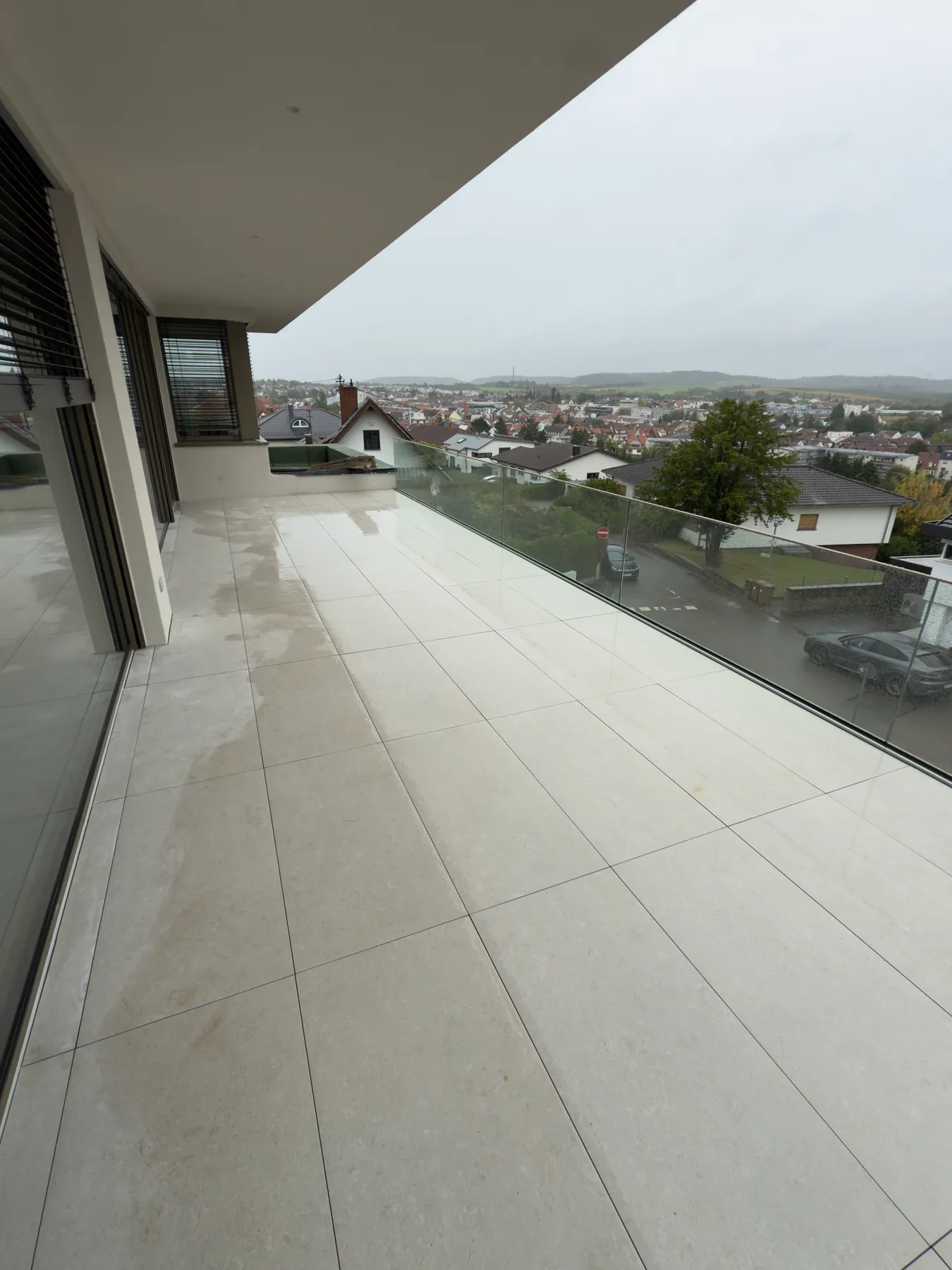 Balkon mit großformatigen Terrassenplatten und Glasgeländer