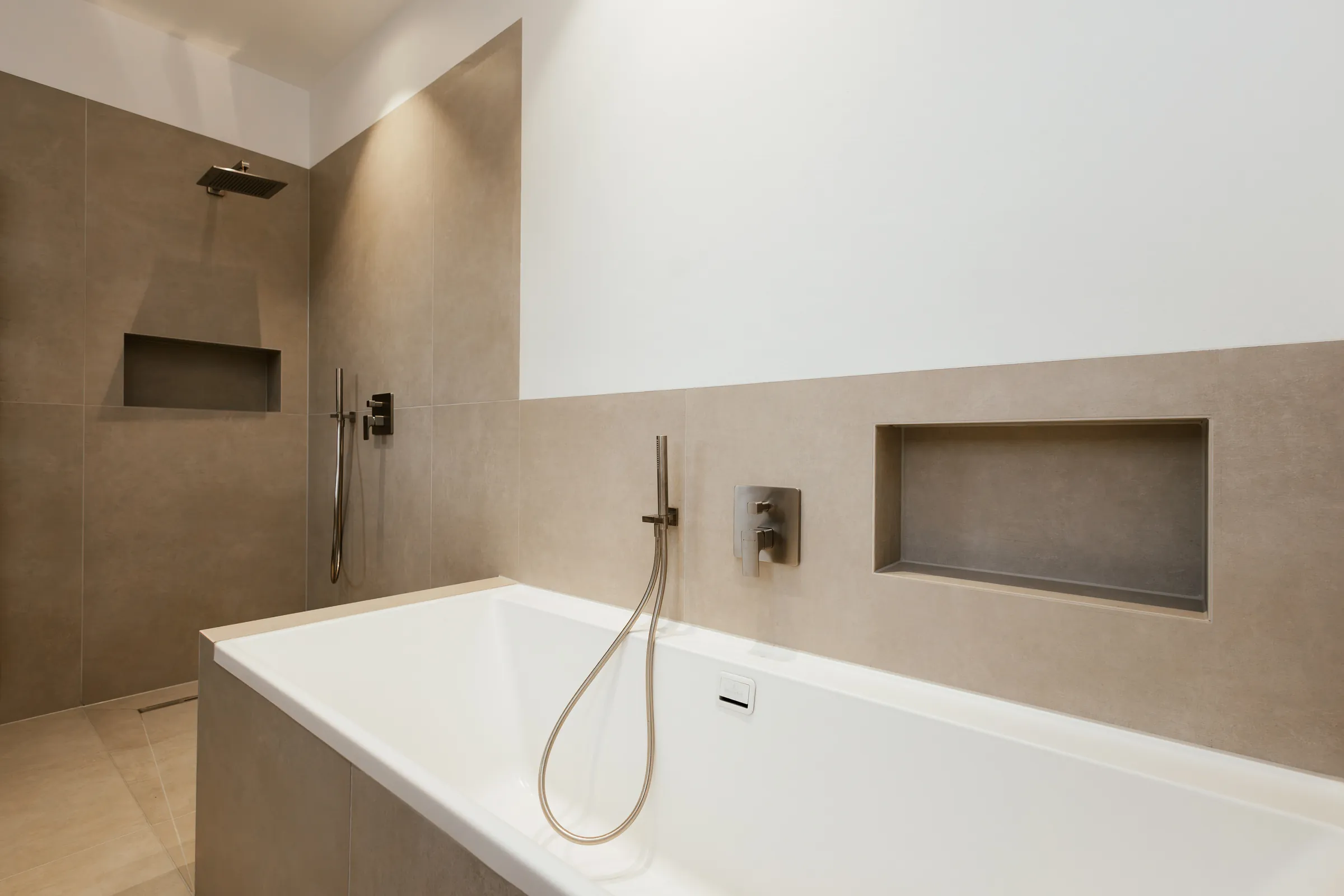 Badewanne mit gefliester Wandnische und Unterputzarmatur in Großformatfliesen